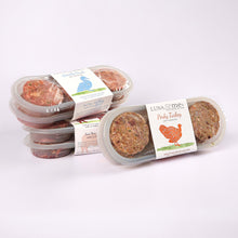 Three plastic containers filled with LUNA & me Indulgence Box raw dog food patties