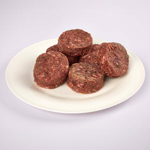 Six LUNA & me Tender Beef raw dog food patties on a white plate