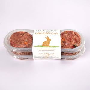 Two stacked plastic containers filled with LUNA & me rabbit raw dog food patties