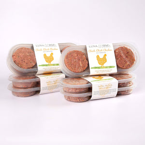 Four stacked plastic containers filled with LUNA & me Value Box raw dog food patties